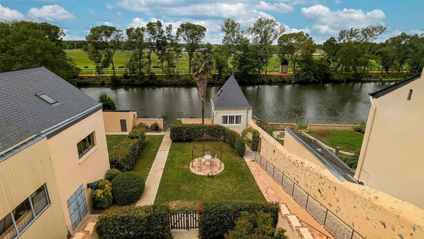 A residential area with a river, a small gazebo, and a well-maintained lawn.