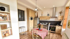 A compact kitchen with wooden cabinets, a dining table with a checkered tablecloth, and a hanging light fixture.