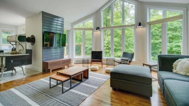 A spacious living room with a large window, a built-in TV, a sofa, a coffee table, and a bench.