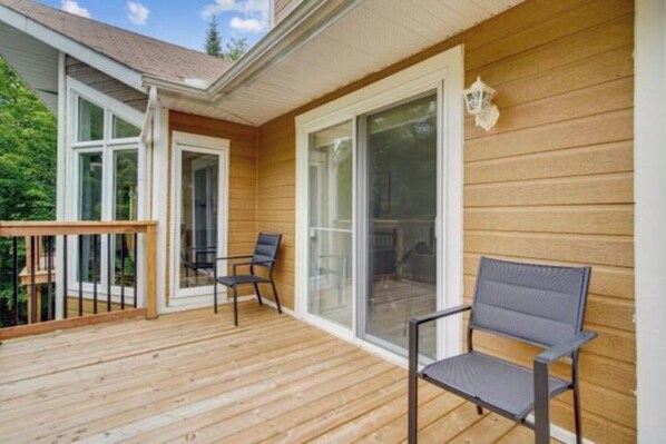 Relax on the deck with a clear view of the surroundings, featuring two chairs and a large sliding glass door.