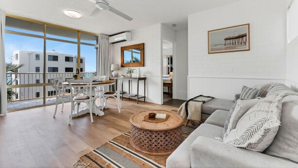 A spacious living area with a balcony, a dining set, and a sofa. - Coolum Beach 1 Bedroom Apartment Ocean View @ Surf Dance (Sunshine Coast)