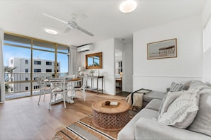 Un vaste espace de vie avec un balcon, une table et des chaises, et un canapé.