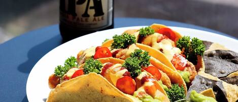 Een bord met taco's, guacamole en een fles Lagunitas IPA bier op een tafel.