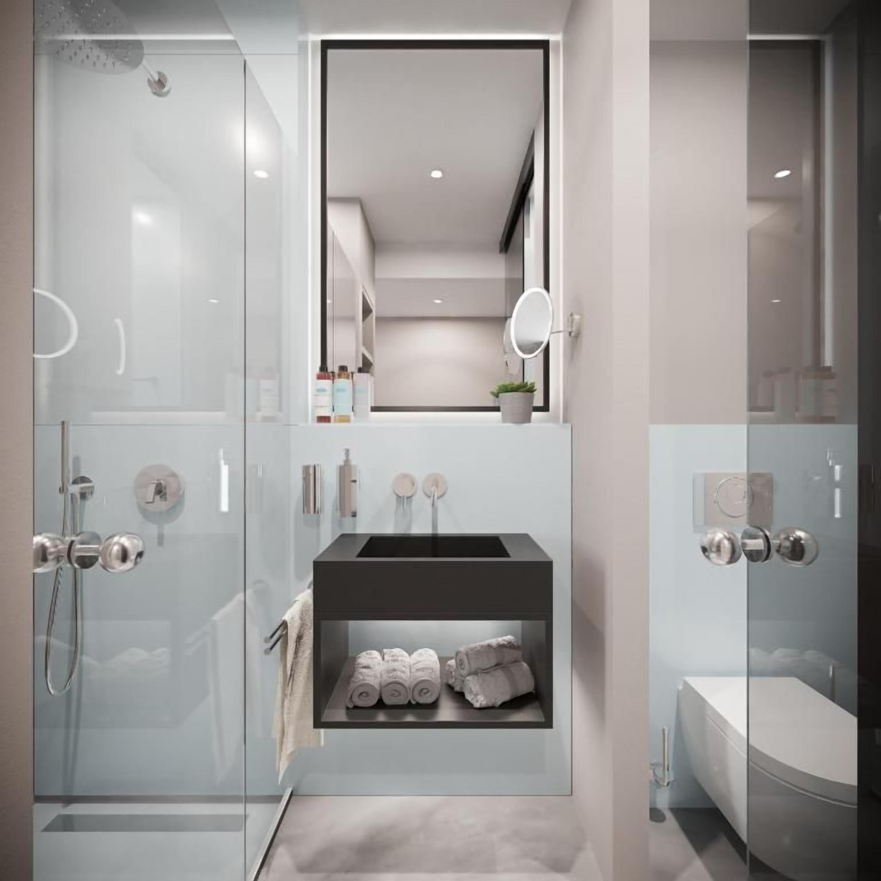 Ein modernes Badezimmer mit einer begehbaren Glasdusche, einem integrierten Waschbecken inklusive Spiegel und einer separaten Toilette.