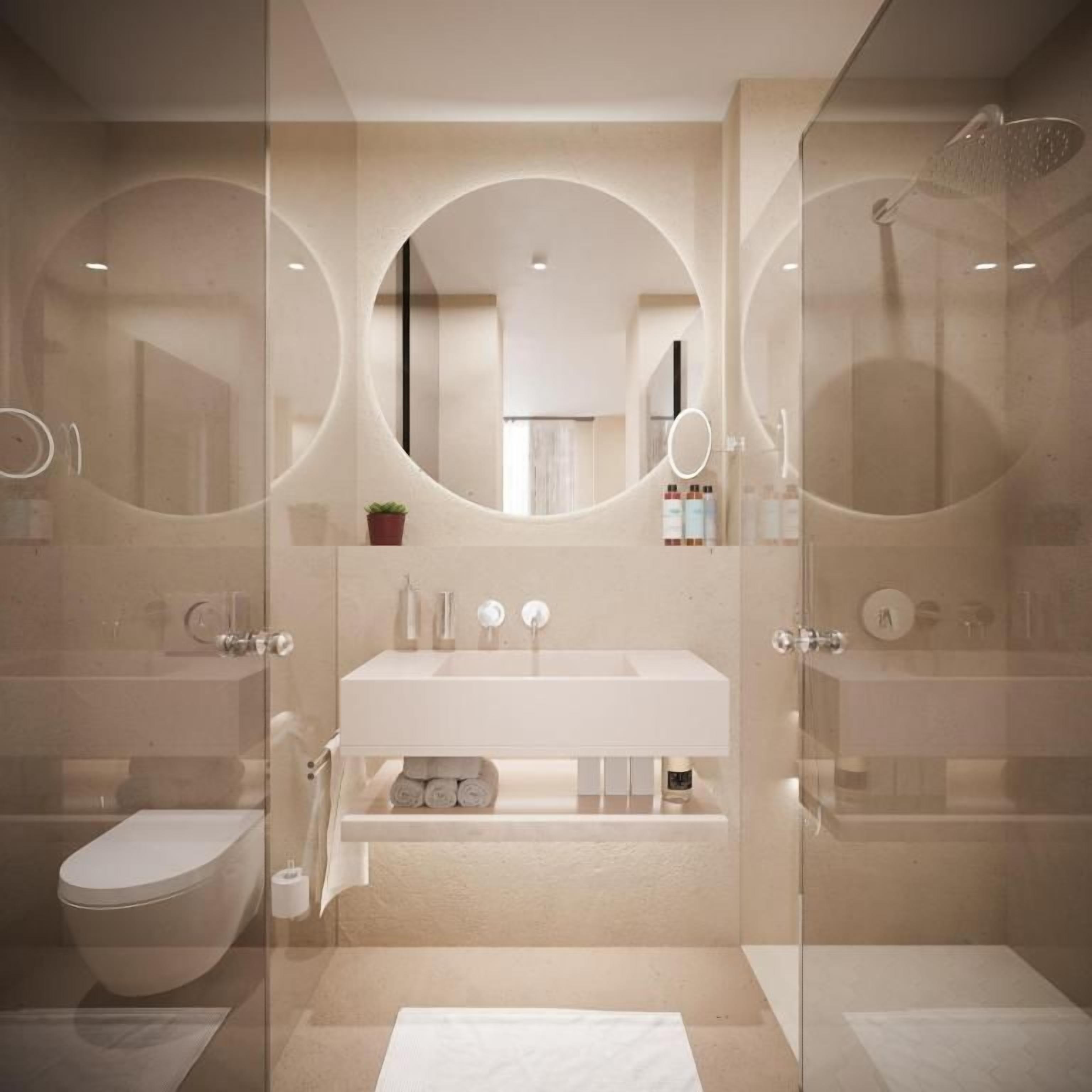 A modern bathroom with a glass-enclosed shower, a white sink, and a round mirror.