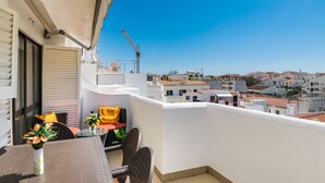 Ein Balkon mit Tisch, Stühlen und einem Blumentopf.