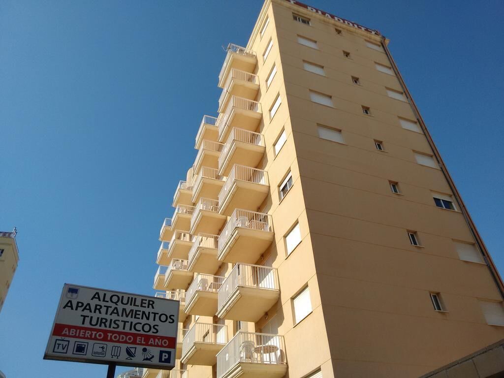 Ein Hochhaus mit einem Schild, das ganzjährig verfügbare Ferienwohnungen bewirbt.