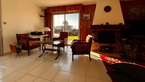 Una sala de estar con chimenea, televisor y comedor con mesa y sillas.
