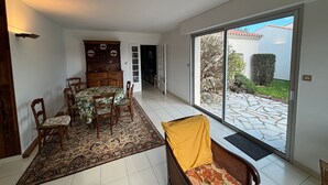 Un comedor con mesa y sillas, un tapete estampado y vistas al exterior a través de un ventanal corredero.