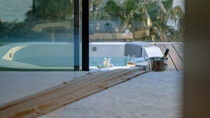 A view from a balcony overlooking a pool and ocean, with a table set with a bottle, glass, and a notepad. - Villa Calma I (Starigrad)