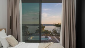A bedroom with a large bed, a sliding glass door leading to a balcony with a hot tub and a view of a body of water. - Villa Calma I (Starigrad)