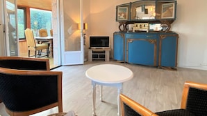 A room with a dining table, two chairs, a TV, and a blue cabinet with a mirror. - Charming House with Garden, WiFi in Central Perros-Guirec - Near Beach and Shops (Perros-Guirec)