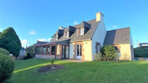 A two-story house with a large front lawn, a conservatory, and a chimney. - Charming House with Garden, WiFi in Central Perros-Guirec - Near Beach and Shops (Perros-Guirec)