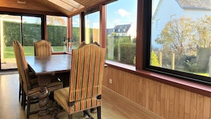 A dining area with a wooden table and chairs, large windows with a view of the outside, and a ceiling with wooden beams. - Charming House with Garden, WiFi in Central Perros-Guirec - Near Beach and Shops (Perros-Guirec)