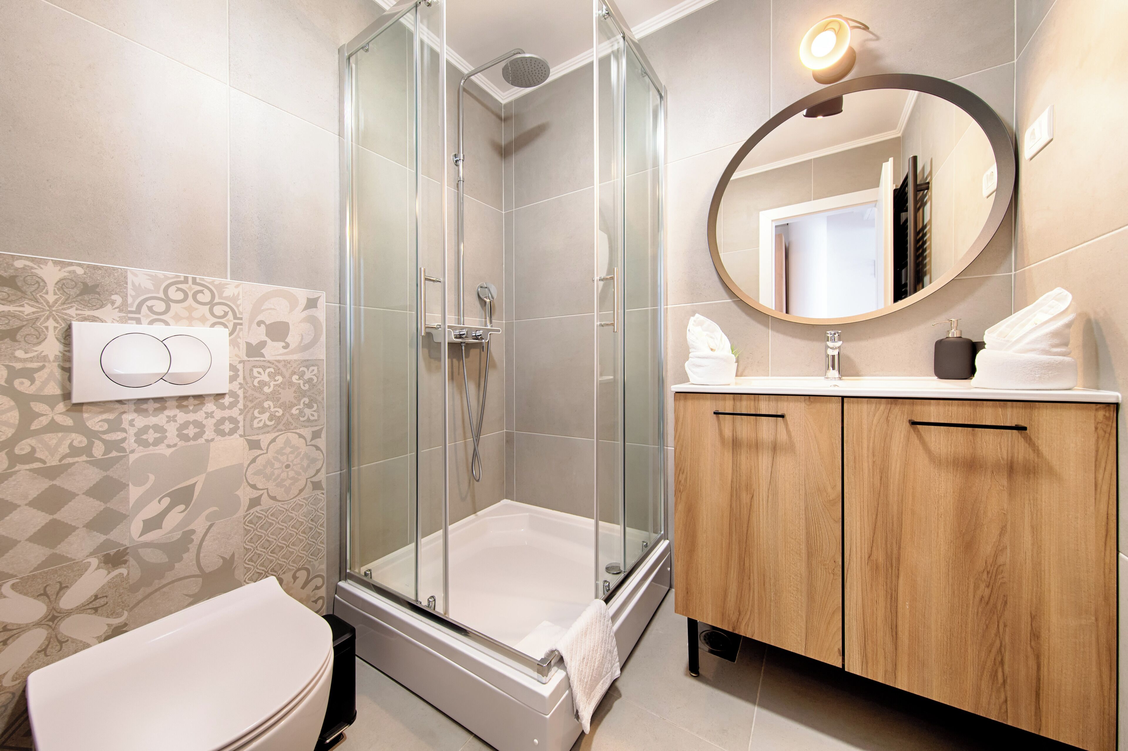 A modern bathroom with a glass-enclosed shower, a white toilet, and a wooden vanity with a mirror.