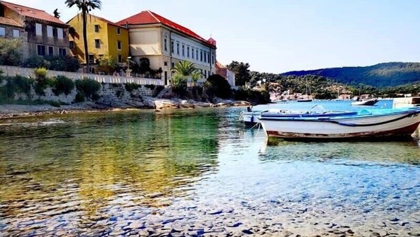 A river with boats, a stone path, and buildings along the riverbank. - 1901-on-sea (Vis)