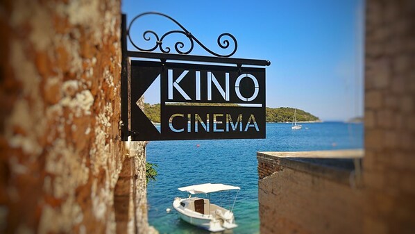 Une enseigne pour le KINO CINEMA, avec vue sur la mer et les bateaux.