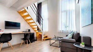 A modern living space with a staircase, a flat-screen TV, a sofa, and a coffee table. - 1901-on-sea (Vis)