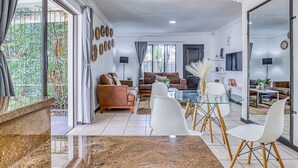 A modern living room with a glass coffee table, leather sofas, and a dining area with white chairs. - Spanish House (Centurion)
