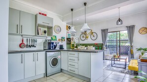 A modern kitchen with white cabinets, a washing machine, and a dining area with a yellow bench. - Spanish House (Centurion)