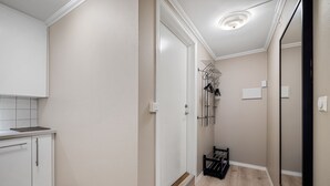 A hallway with a white door, a coat rack, and a small shelf. - Holmboe Apartment  (Bergen)
