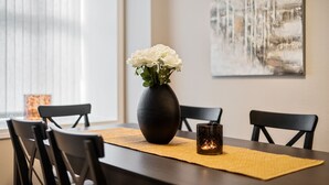 A dining table with a vase of white flowers, a candle, and a placemat. - Holmboe Apartment  (Bergen)