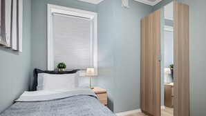 A bedroom with a bed, bedside table, lamp, and a wardrobe. - Holmboe Apartment  (Bergen)