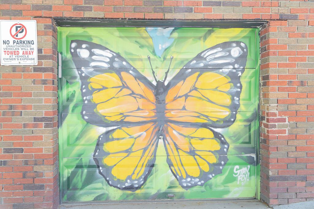 A mural of a yellow and black butterfly on a garage door.