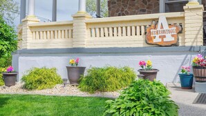 A covered porch with a stone wall, potted plants, and a sign reading "The Ranch Inn 1900". - The Jewel: Spacious 3 Bdrm Victorian Apt w/ Sauna, Parking. Just 10 mins To NYC! (Jersey City)