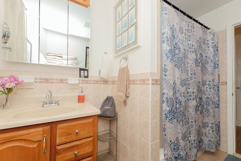 A bathroom with a sink, mirror, and a shower curtain with a blue and white pattern.