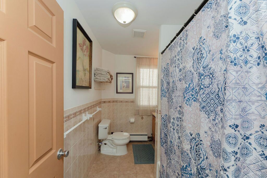 A bathroom with a toilet, sink, and shower curtain.