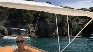 A person sitting on a boat with a canopy, surrounded by water and rocky cliffs. - BRAND NEW APARTMENT JUST MINUTES FROM THE SEA (Sarzana)