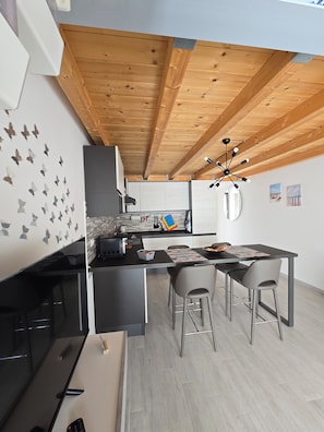 A modern kitchen with wooden beams, a dining area with chairs, and a kitchen island.