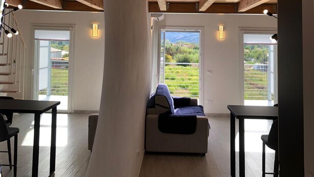 A spacious loft with a high ceiling, wooden beams, a large skylight, and a view of the countryside. - BRAND NEW APARTMENT JUST MINUTES FROM THE SEA (Sarzana)