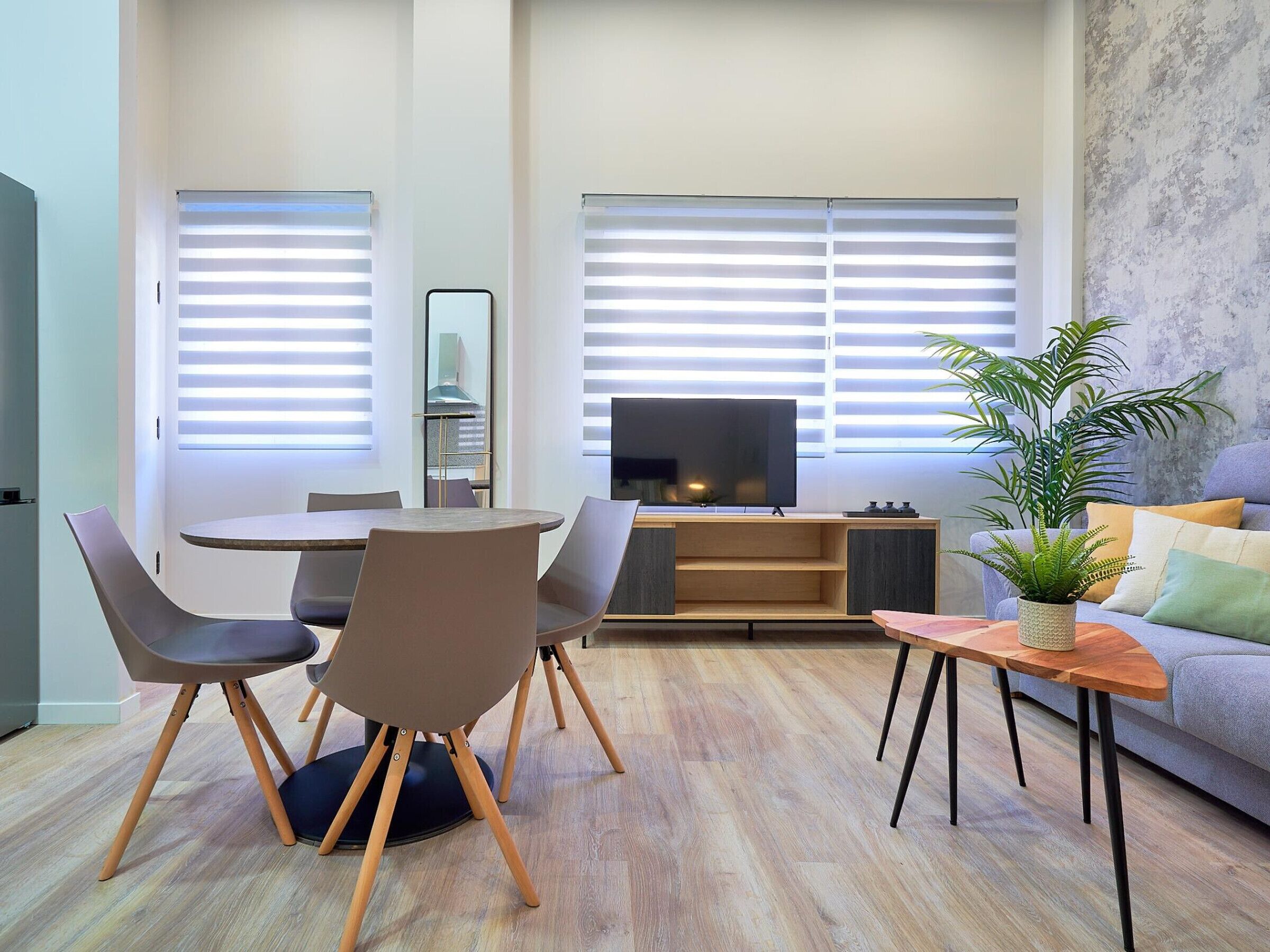 Una sala de estar moderna con comedor, televisor de pantalla plana y planta en maceta.