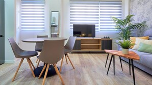 Una sala de estar moderna con comedor, televisor de pantalla plana y planta en maceta.