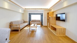 Una sala de estar moderna con sofá, mesa de centro, televisor y estanterías de madera.
