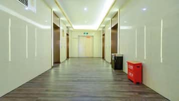 A long, narrow hallway with a wooden floor, white walls, and a ceiling with recessed lighting.