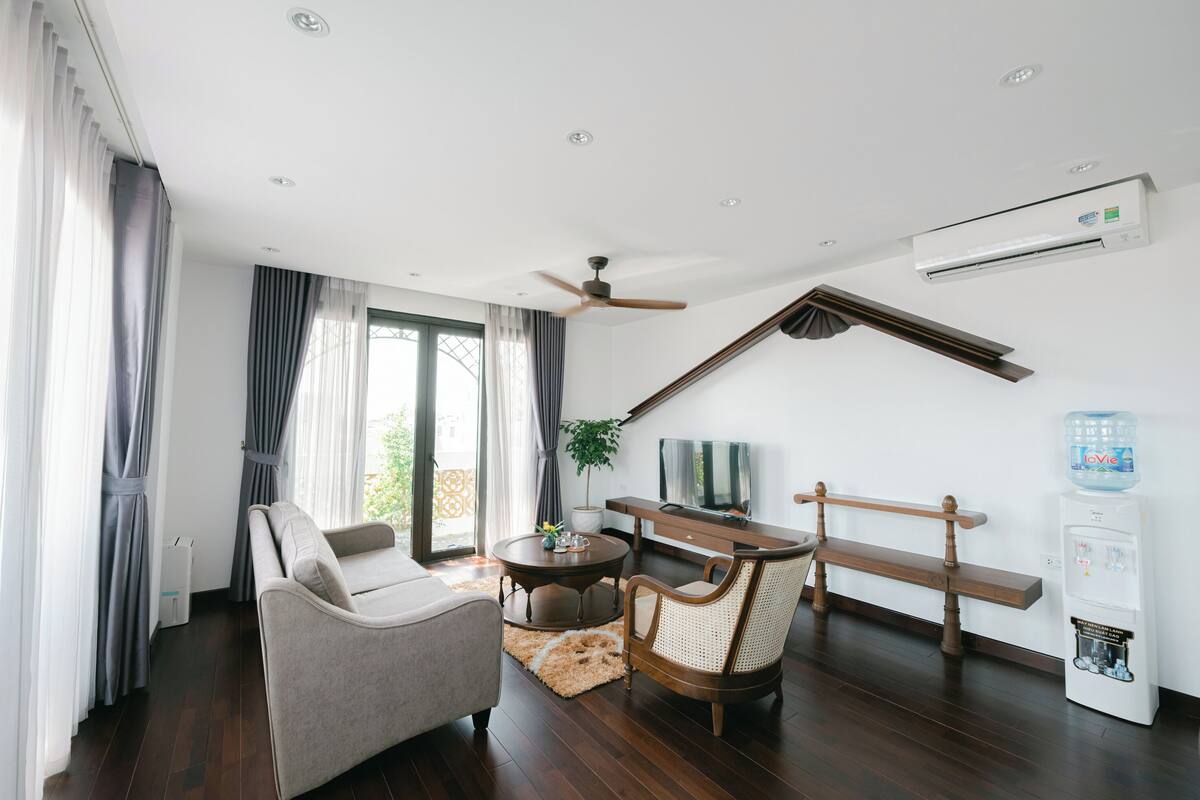 A modern living room with a sofa, two chairs, a coffee table, a TV, and a water dispenser.