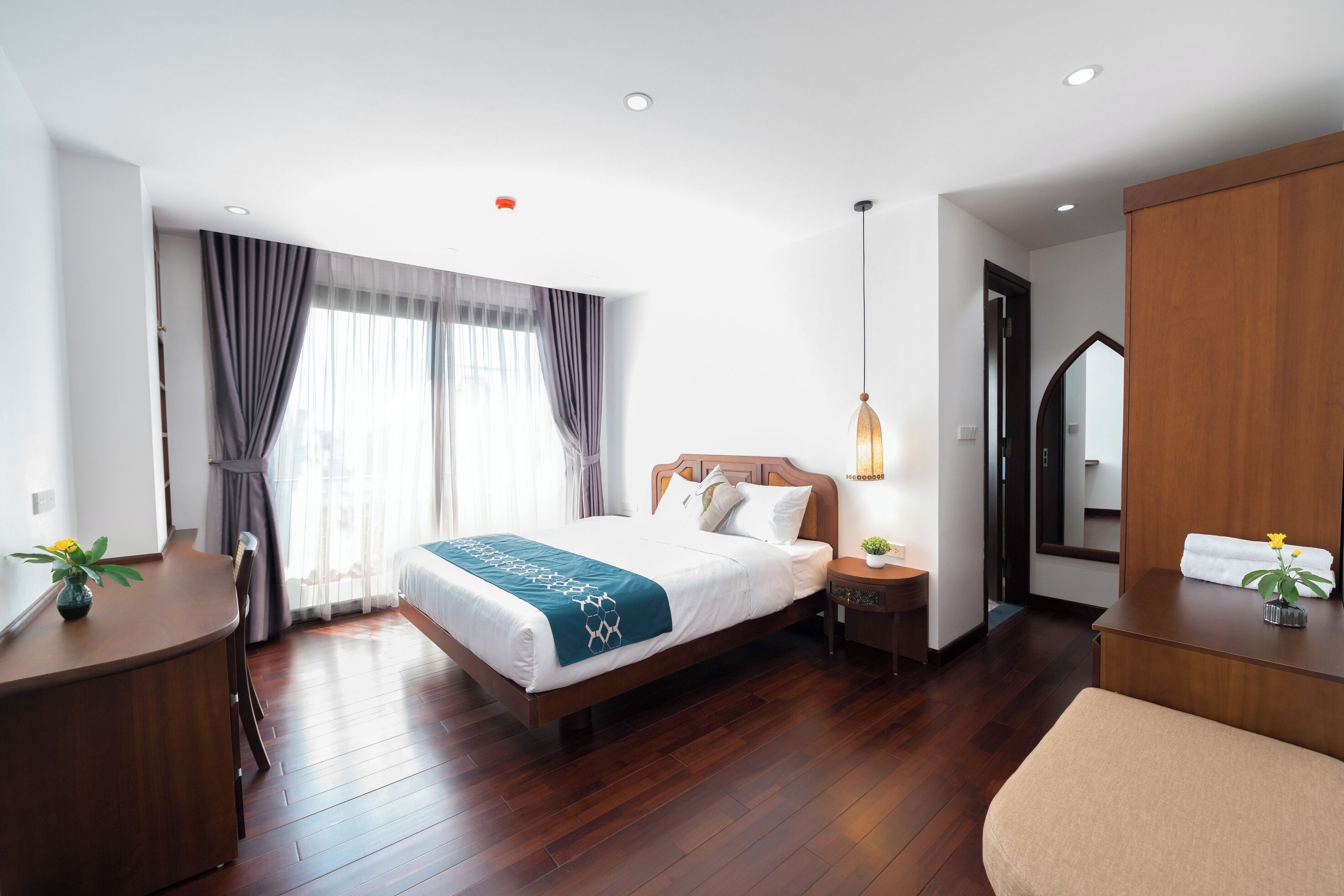 Una habitación de hotel moderna con una cama de madera, un escritorio y un espejo.