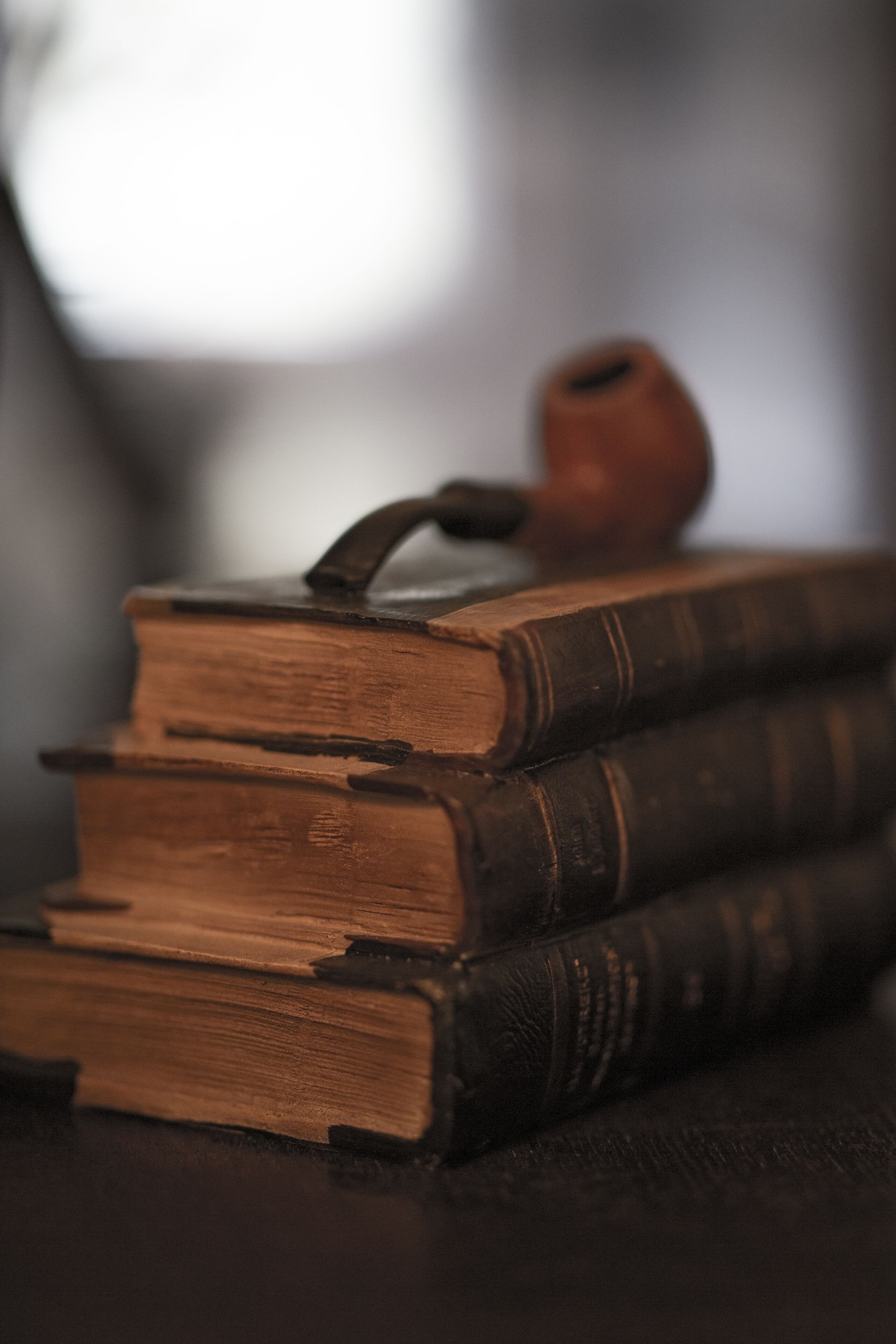 A stack of old books with a pipe on top.