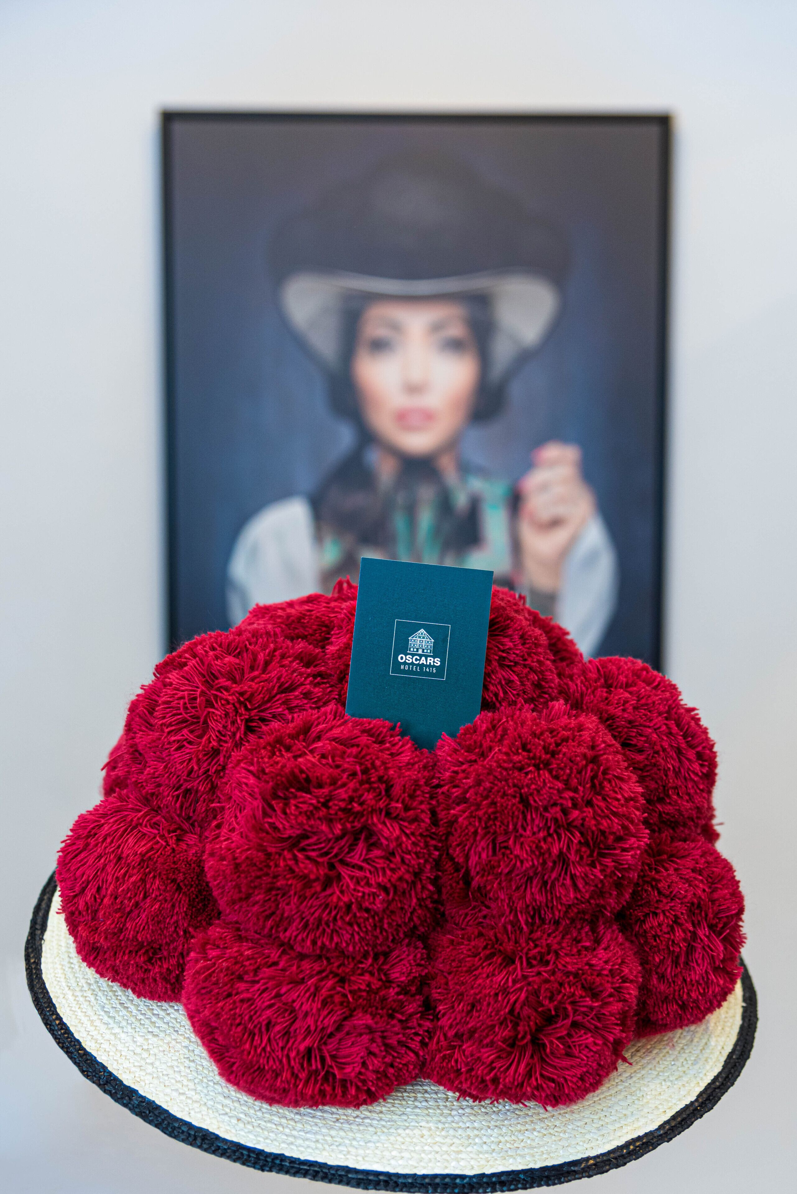 A plush red item with a tag on it, placed on a round, woven base.