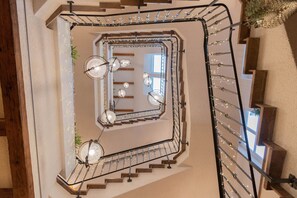 A spiral staircase with a metal railing, wooden steps, and string lights. - OSCARS Hotel 1415 (Bad Liebenzell)