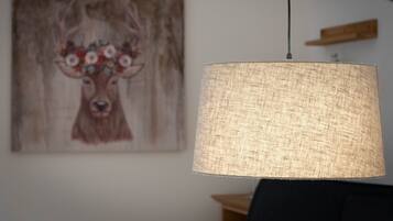 A lamp with a textured shade and a painting of a deer on the wall.