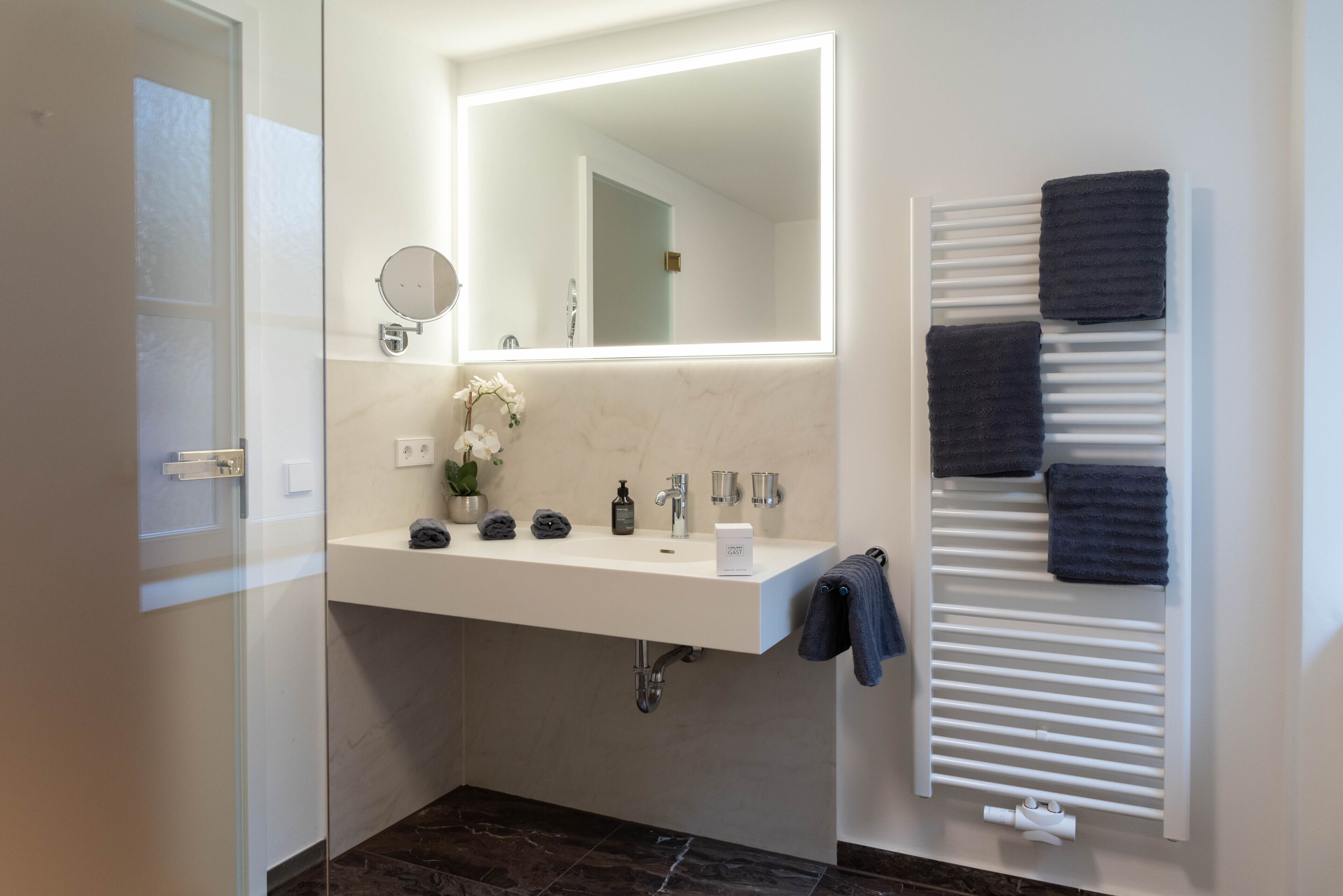 A modern bathroom with a white sink, mirror, and towel rack.