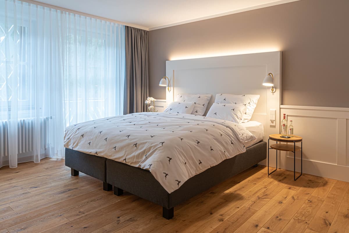 A modern bedroom with a large bed, a bedside table, and a nightstand.