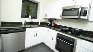 Una cocina moderna con armarios blancos, microondas integrado, lavavajillas y estufa.