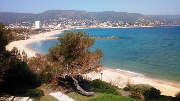 Ein Küstenblick mit Strand, blauem Himmel und einer entfernten Stadtlandschaft.