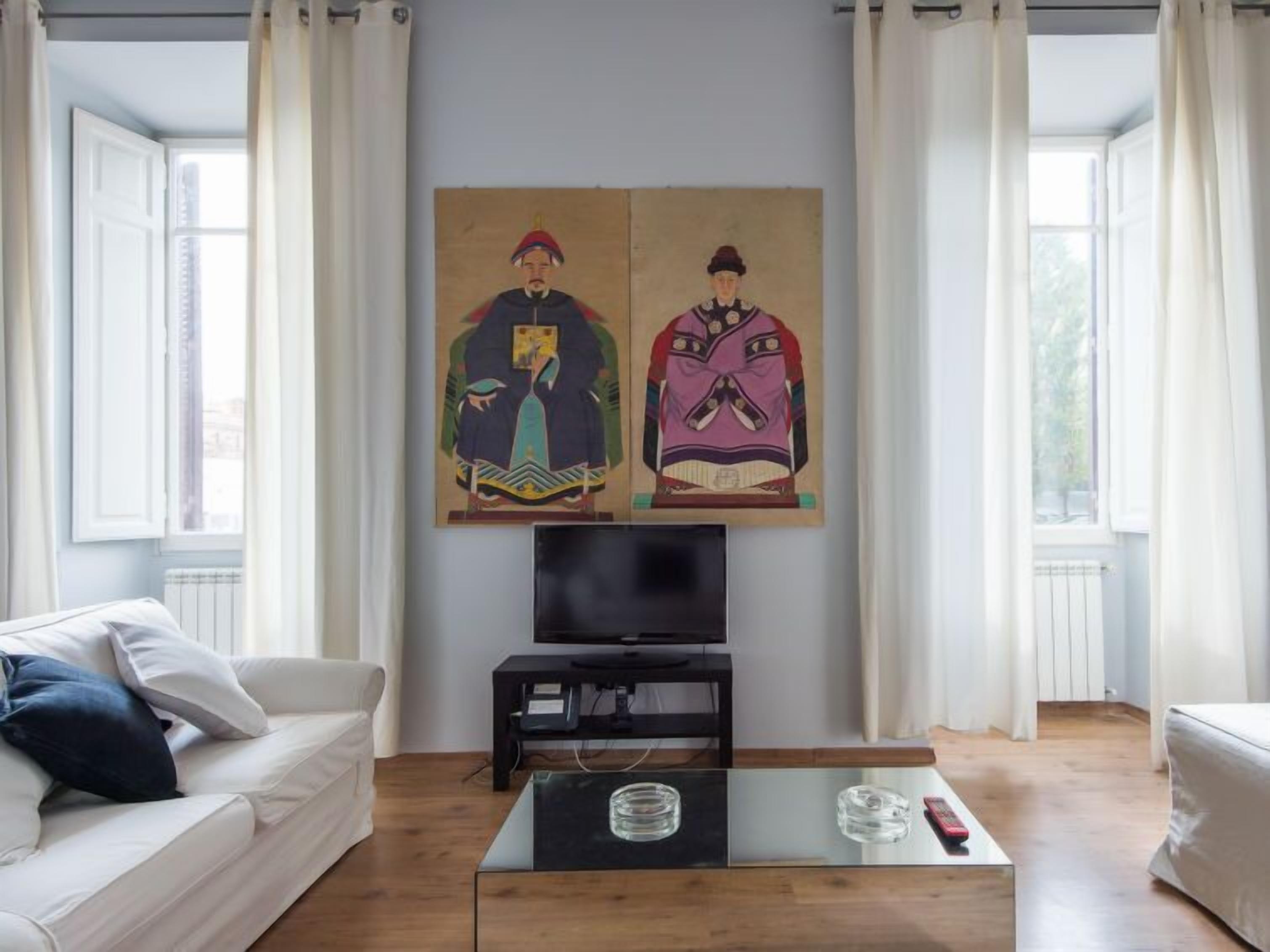 Un salon avec un canapé, une table basse, un téléviseur et deux tableaux accrochés au mur.