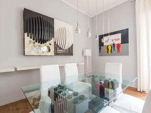 Un comedor moderno con una mesa de vidrio, sillas blancas y obras de arte contemporáneas en las paredes.